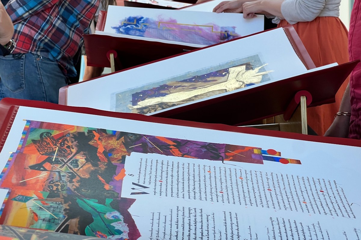 A close up of viewers examining several volumes of The Saint John's Bible Heritage Edition on display in Regent's Dal Schindell Gallery.